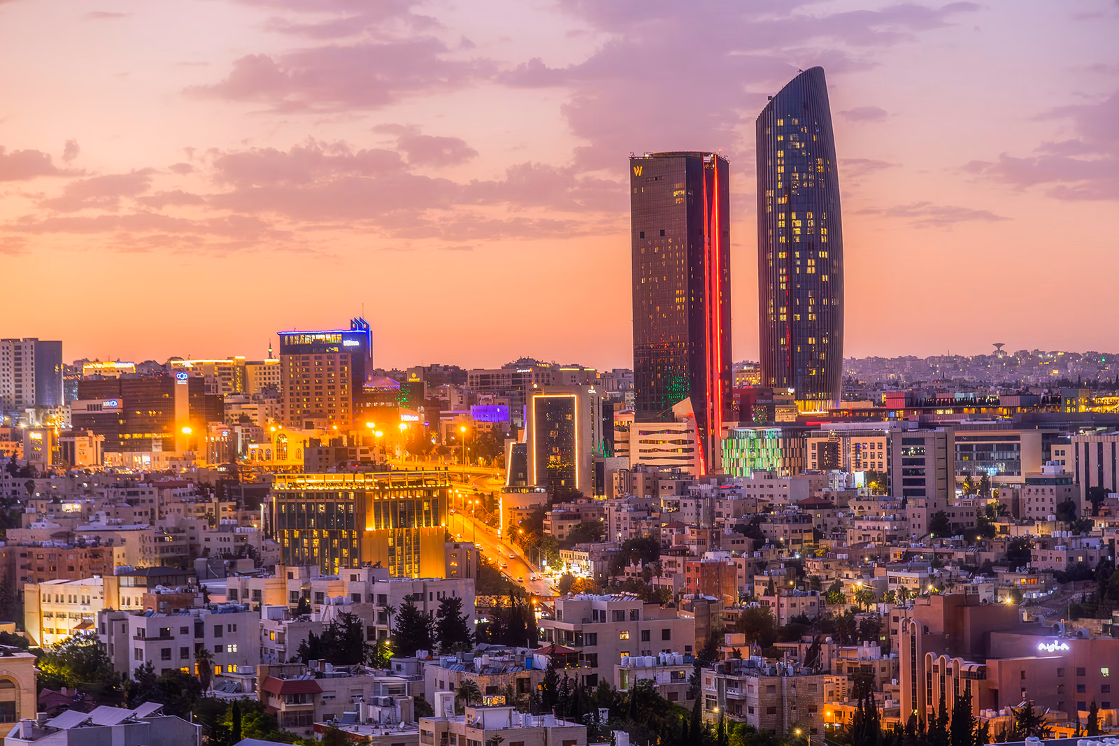 Amman city white-stone architectural skyline across the rolling hills at sunset, Jordan